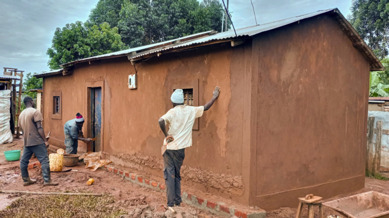 A homeowner standing proudly in her newly finished earthen home